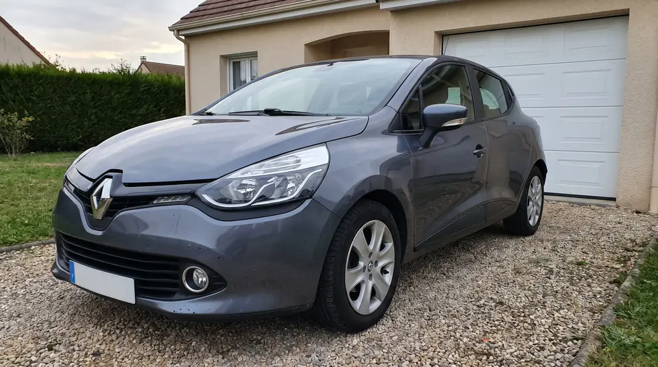 Renault Clio IV grise garée devant un garage